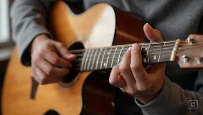 Close-up van handen die op een akoestische gitaar spelen.