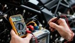 Het controleren van de spanning van de motorfietsaccu met een multimeter.