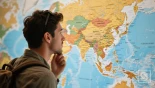 Een reiziger die naar een wereldkaart kijkt en Zuidoost-Azië markeert.