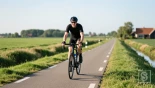 Een fietser die op een goed onderhouden fietspad door het Nederlandse landschap rijdt.