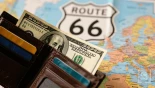 Close-up van een portemonnee met Amerikaanse dollars en een Route 66 kaart op de achtergrond.