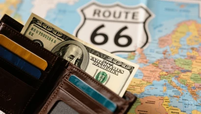 Close-up van een portemonnee met Amerikaanse dollars en een Route 66 kaart op de achtergrond.