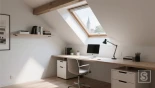 Minimalistische zolderwerkplek met een bureau bij een dakraam.