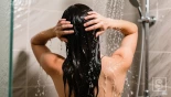 Vrouw spoelt haar haar uit in de douche.