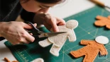 Persoon knipt viltfiguren uit met een schaar.