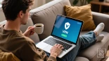 Persoon installeert VPN app op laptop op bank.